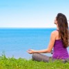 Beautiful woman sitting near the ocean learning to let go and let it all be.