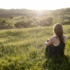 Don't fall in love with his potential. A beautiful woman sits in the grass and looks out across the valley at a beautiful sunset.