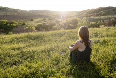 Dont-fall-in-love-with-his-potential-Woman-looking-off-into-sunset Don't fall in love with his potential. A beautiful woman sits in the grass and looks out across the valley at a beautiful sunset.