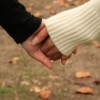 Real Love. Real Love never leaves you hanging. Real Love never leaves you guessing. Real love never hurts. A man and woman are holding hands walking through an autumnal field of fallen leaves.